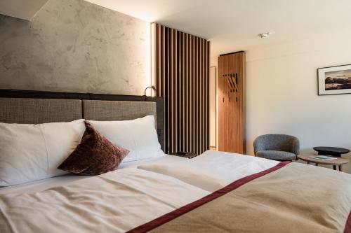 a bedroom with a large white bed and a chair at Hotel Salzburg in Saalbach Hinterglemm