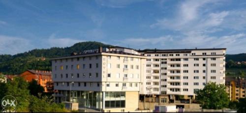 um grande edifício branco com uma montanha ao fundo em Apartment B&B em Vogošća