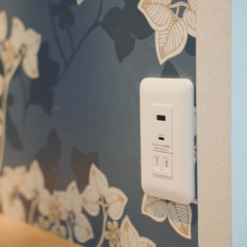 a white electrical outlet on a wall with flowers at The Box House in Furano