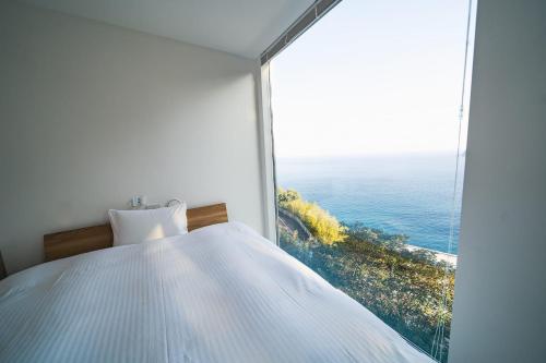 a bedroom with a white bed and a large window at White House Atami in Atami