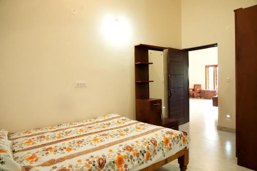 a bedroom with a bed with a floral comforter at Chimneys Homestay - Full House, Near to Falls & Trek in Sakleshpur