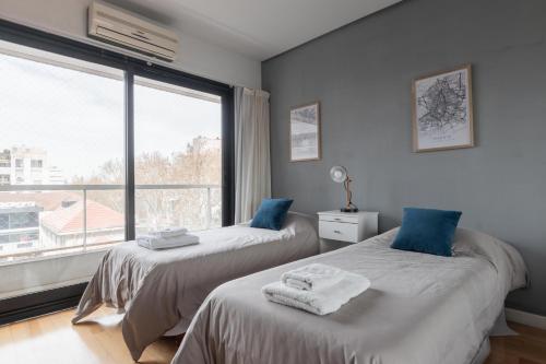 2 camas en una habitación con ventana grande en Fliphaus Nicaragua 6000 - 2 Bd Live Hotel en Buenos Aires