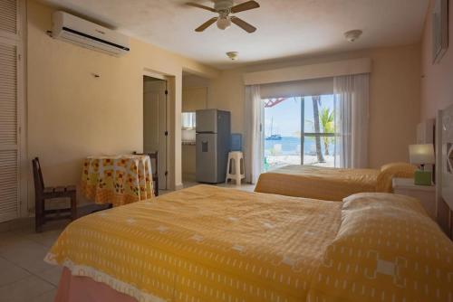 a bedroom with two beds and a kitchen with a window at Marysol beachfront next to nomads d6 in Isla Mujeres