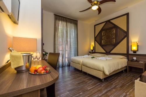 a hotel room with a bed and a table with a bowl of fruit at Hotel Riviera in Melide
