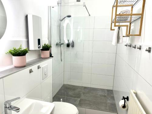 a white bathroom with a shower and a sink at Das Berg Apartment Rüttenscheid, Netflix, nahe Messe, Klinikum in Essen