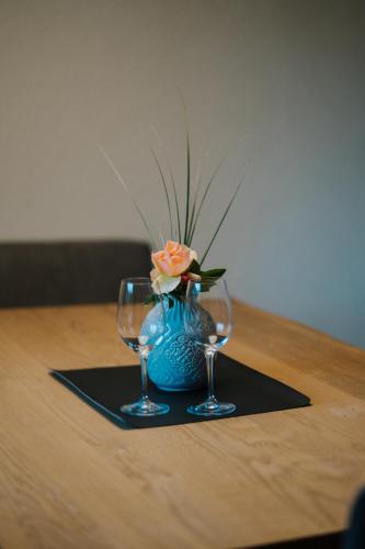 a blue vase with a flower and two wine glasses at Nockventure Ferienhaus Gnesau in Gnesau