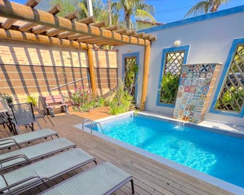 a swimming pool with a deck and a house at VELINN Pousada Iguana Azul in Ilhabela