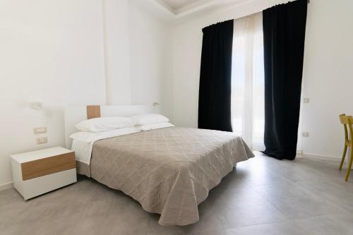 a white bedroom with a bed and black curtains at Sa Pasadina in Àrbatax