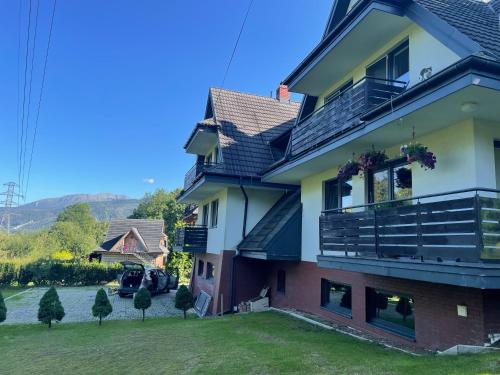 une maison avec un balcon et une cour dans l'établissement Apartament Idylla, à Zakopane