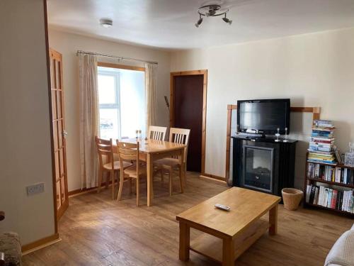 a living room with a table and a television at 2 Bedroom house overlooking Pierowall Bay, Westray in Pierowall