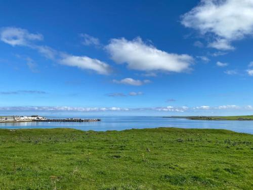 a large body of water with a pier in the distance at 2 Bedroom house overlooking Pierowall Bay, Westray in Pierowall