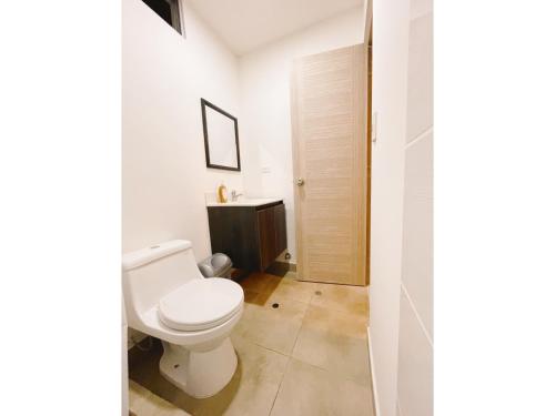 un bagno bianco con un water e un lavandino di Amplia habitación privada con baño privado y TV a Lima