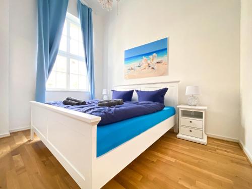 a bedroom with a bed with blue sheets and a window at Große 3-Raum Luxus-Unterkunft mit 2 Bädern, Waschtrockner & kostenfreier Tiefgarage in Innenstadtnähe in Leipzig