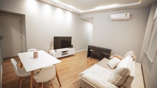 a living room with a couch and a table and a tv at Apartamento no bairro do Flamengo. Reformado e aconchegante! in Rio de Janeiro