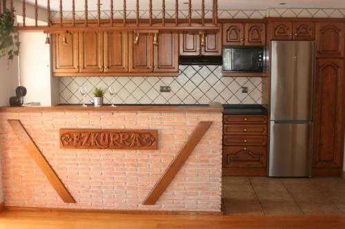 una cocina con armarios de madera y una pared de ladrillo en Gartzinea, amplia y preciosa vivienda rural, en Ezkurra