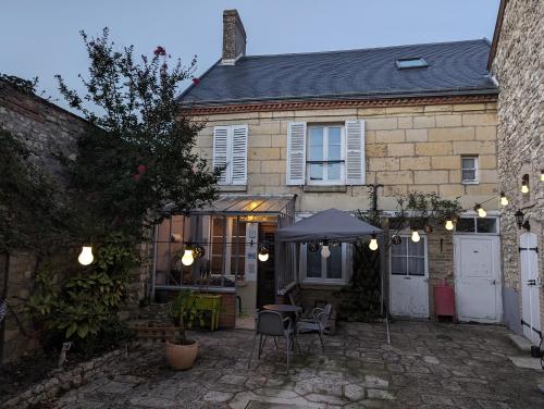 een huis met een patio met een tafel en een parasol bij La cachette sous l'escalier, le gîte ensorcelé 