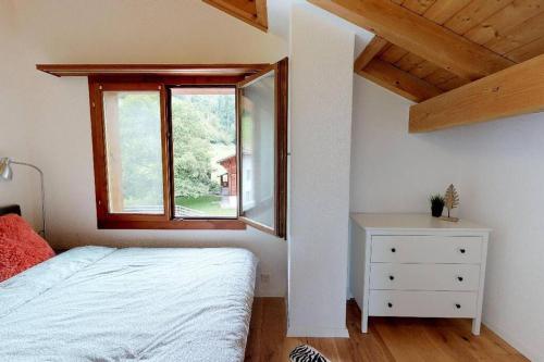 ein Schlafzimmer mit einem Bett, einem Fenster und einer Kommode in der Unterkunft Maisonette 4.5 Zimmer, Nähe Ballenberg in Hofstetten 