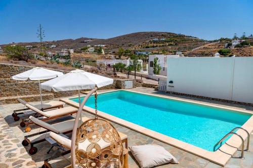a swimming pool with lounge chairs and umbrellas next to at Aqua Blu Syros 1,3 in Posidhonía