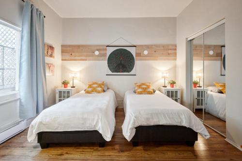 1 dormitorio con 2 camas y espejo en MtlVacationRentals - MTL ZOO, en Montreal