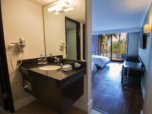 a bathroom with a sink and a large mirror at Hotel Lucerna Tijuana in Tijuana