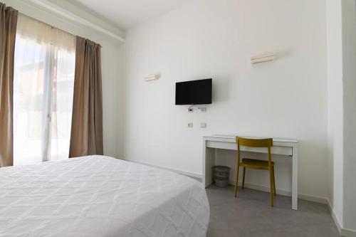 a bedroom with a bed and a desk with a television at Sa Pasadina in Àrbatax