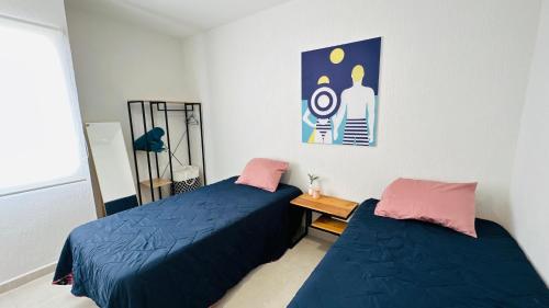 a bedroom with two beds and a picture on the wall at Bonito departamento playa/planta baja in Playa del Carmen