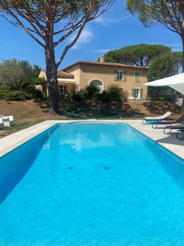 une grande piscine bleue devant une maison dans l'établissement Bastide de l'Hermitan - Golfe de Saint Tropez, à Cogolin