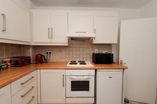 cocina con armarios blancos y fogones en GoldenGlow Apartment 15 MIN Airport, en Dublín