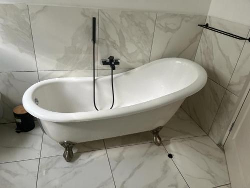 a white bath tub in a bathroom with white tiles at Soft petal in Pretoria