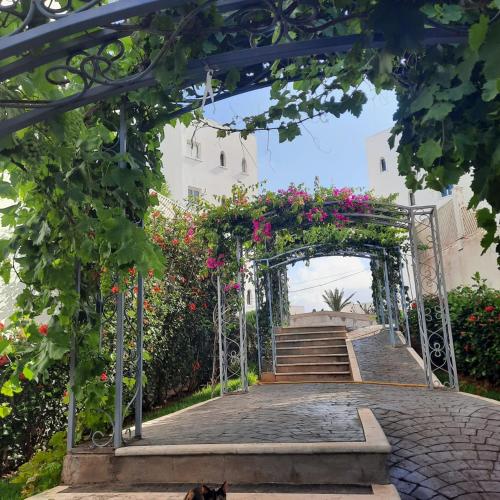an archway with flowers on it and stairs at Appartement haut standing jardins Assilah in Asilah