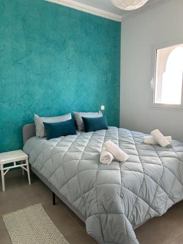 a bedroom with a large bed with a blue wall at Les magnifiques jardins d’Assilah in Asilah