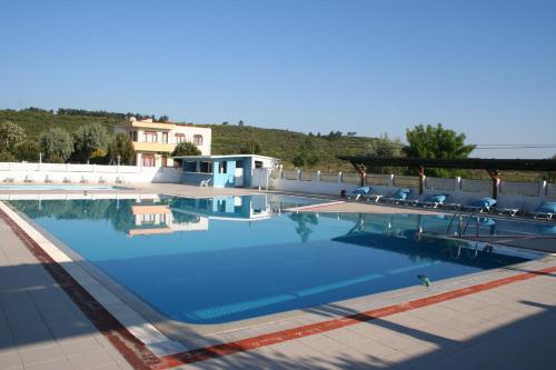 a large swimming pool with chairs and a building at Kum Hotel in Eceabat