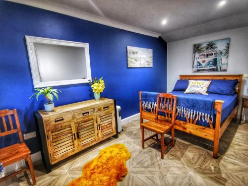 a bedroom with blue walls and a bed and chairs at The Lodge in Newton Stewart