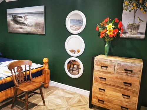 a bedroom with green walls and a chair and a dresser at The Lodge in Newton Stewart