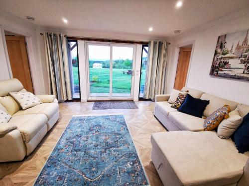 a living room with two couches and a large window at The Lodge in Newton Stewart