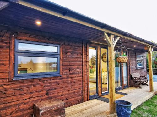 a wooden cabin with a large window on a deck at The Lodge in Newton Stewart