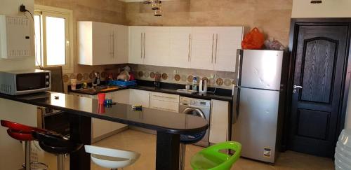 cocina con nevera, mesa y sillas en Telal Ground Floor 2 bedroms en Ain Sokhna