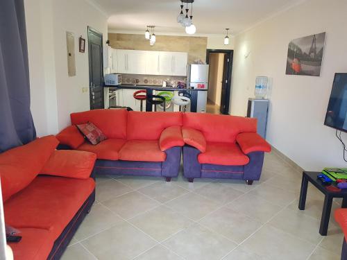 sala de estar con sofá rojo y cocina en Telal Ground Floor 2 bedroms en Ain Sokhna