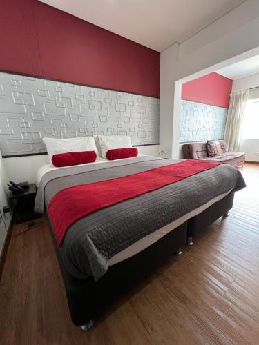 a bedroom with a large bed with a red wall at Hotel Florencia Plaza in Medellín