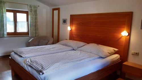 a bedroom with a large bed with a wooden headboard at Doppelzimmer Herzogbauer in Saalfelden am Steinernen Meer