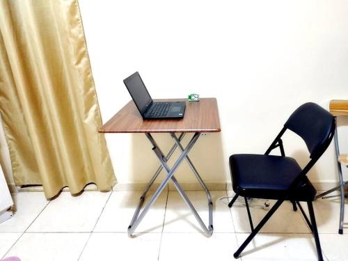 a laptop computer sitting on a table with a chair at Live Like A Family Home Away From Home in Sharjah