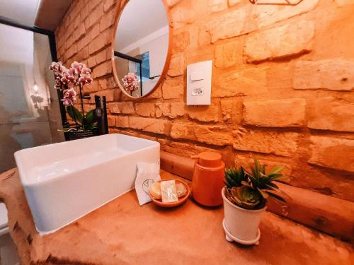 a bathroom with a white sink and a stone wall at Recanto das Videiras - Casa em Vinícola in Itapira