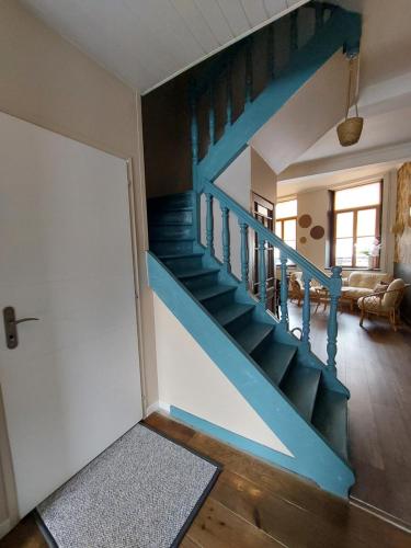 eine blaue Treppe in einem Wohnzimmer mit einer Tür in der Unterkunft Natif 4 personnes in Aire-sur-la-Lys