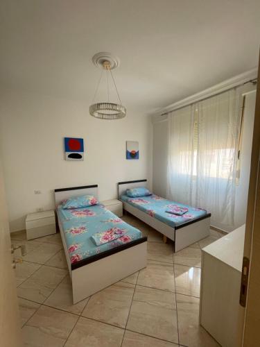 ein Schlafzimmer mit zwei Betten und einem Kronleuchter in der Unterkunft Appartamento Vista Mare a Valona 5 persone in Vlorë