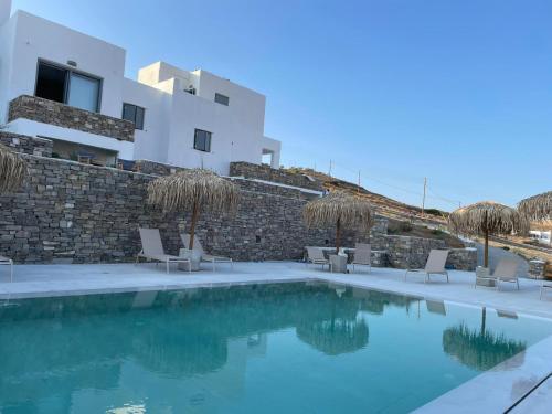 a swimming pool with chairs and a building in the background at Krotiri View Paros in Krotiri