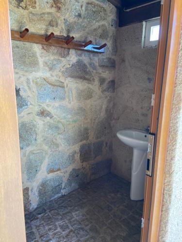 a bathroom with a stone wall and a sink at Casa das Portelas in Ponte de Lima