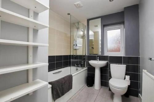 een badkamer met een toilet, een wastafel en een spiegel bij Lawnswood Place in Manchester