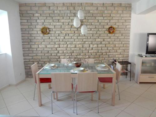 comedor con mesa, sillas y pared de ladrillo en Villa Dijana en Prvić Šepurine