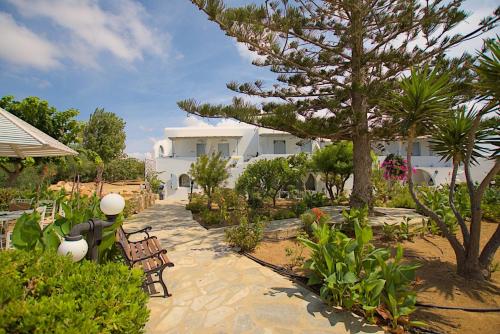 a garden with chairs and a tree and a building at Maroussa Studios in Agia Anna Naxos