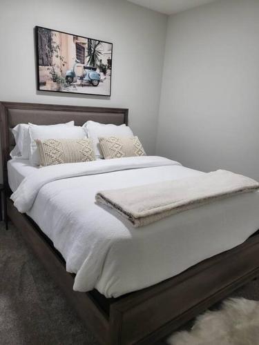 a large bed with white sheets and pillows at Serene Haven - 1 bedroom apartment. in Calgary